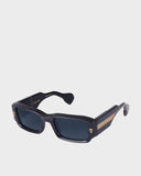 Black sunglasses with gold accents on a light gray background